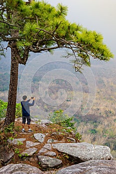 A man taking picture at viewpoint on edge of a cliff nature background