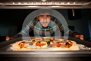 Man taking pizza from oven