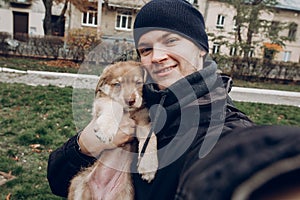 man taking selfie with adorable brown puppy with amazing blue eyes on background of autumn park. space for text. faithful friend