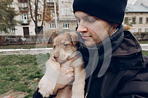 man taking selfie with adorable brown puppy with amazing blue eyes on background of autumn park. space for text. faithful friend