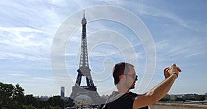 Man taking a selfie in front of Eiffel tower in Paris