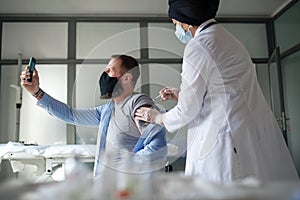 Man taking selfie when getting vacinated, coronavirus and vaccination concept.