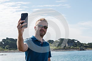Man taking a selfie with a smartphone at the lakeside