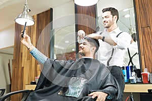 Man Taking Selfportrait On Smartphone While Hairdresser Styling