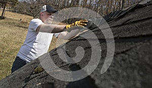 Man taking shingles off a shed roof