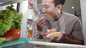 man taking some food out from the fridge to eat by himself while hungry