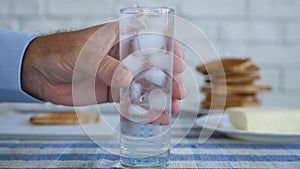 Man Taking from the Table a Glass with Ice Cubes and Fresh Water