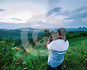 A man is taking video of the mountains during sunrise in Wang Kelian, Perlis, Malaysia