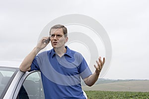 Man talking on cell phone beside a car