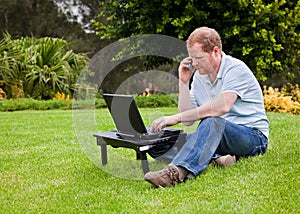 Man talking on cell phone in front of a laptop