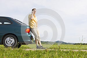 Man talking on cell phone beside his car