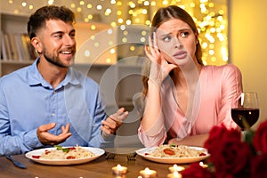 Man talking earnestly, woman annoyed at romantic dinner