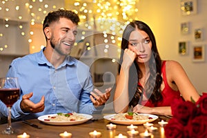 Man talking happily, woman looking bored during a dinner date