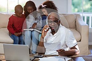 Man talking on mobile phone while checking bills