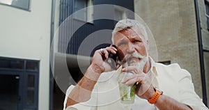 A man is talking on a mobile phone while walking outdoors