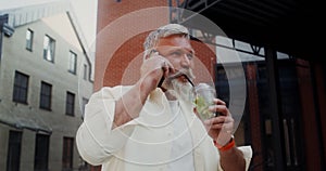 A man is talking on a mobile phone while walking outdoors