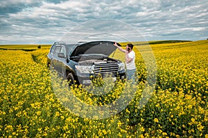 Man talking on the phone near the car with the opened hood