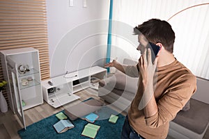 Man Talking On Phone And Pointing At Stolen Television photo