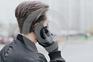 A man is talking on the phone in a protective black glove