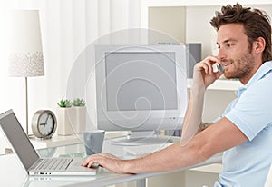 Man talking on phone using computer