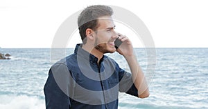 Man talking on phone walking on the beach