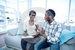 Man talking with pregnant wife while writing on paper