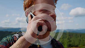 Man talking on smartphone in mountains. Traveler having phone conversation