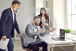 Man talking to his business colleagues and showing something on a laptop computer