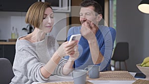 Man talking to woman distracting spouse from social media on smartphone. Irritated wife ignoring husband surfing