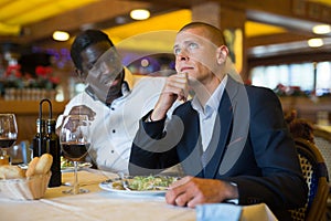 Man talking with upset friend at restaurant