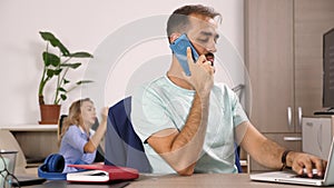 Man talks on the cellphone while a woman is watching TV in the background