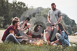 Man talks with interest. Group of people have picnic on the beach. Friends have fun at weekend time