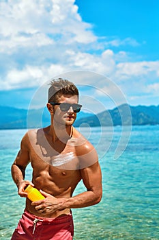 Man Tanning Using Sun Block Body Cream On Summer Beach
