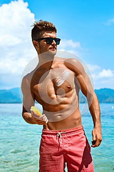 Man Tanning Using Sun Block Body Cream On Summer Beach