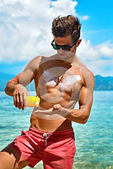 Man Tanning Using Sunscreen Cream On Body Skin. Summer