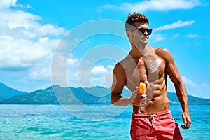 Man Tanning Using Sunscreen Cream On Body Skin. Summer