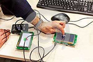 Man tapping, interacting with an lcd touch screen display on a single board microcontroller Progamming open source hardware