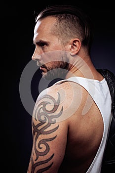 A man with tattooes on his arms. Silhouette of muscular body. caucasian brutal hipster guy with modern haircut, looking