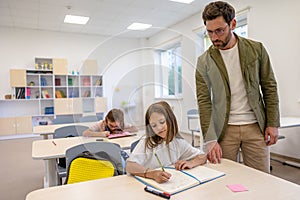 Man teacher helping pupils during lesson in school.