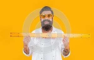 man teacher hold measuring ruler isolated on yellow. man hold measuring ruler in studio.