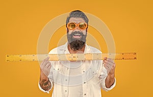 man teacher hold measuring ruler isolated on yellow. man hold measuring ruler in studio.