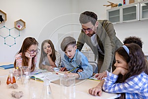 Man teacher with kids during chemistry lesson in school classroom.