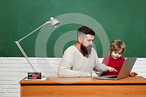 Man teaches child. Teacher helping pupils studying on desks in classroom. Concept of education and teaching. Chalkboard