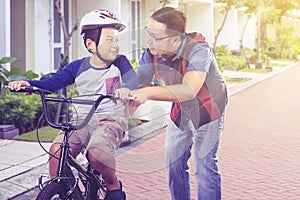 Man teaches his boy to ride bike on housing road