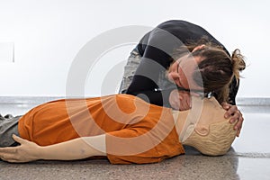 Man teaching cardiopulmonary resuscitation with a dummy on a white background. Checking if the injured person breathes with the
