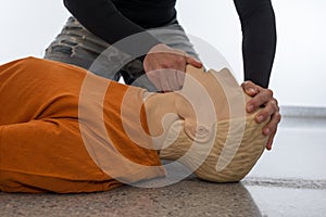 Man teaching cardiopulmonary resuscitation with a dummy on a white background. Front-chin Maneuver and airways opening