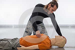 Man teaching cardiopulmonary resuscitation with a dummy on a white background. Pinching the injured to see if he responds to pain