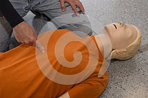 Man teaching cardiopulmonary resuscitation with a dummy on a white background. Pointing the externum to find the right spot for