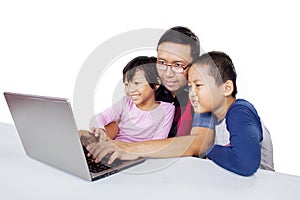 Man teaching his children how to use a laptop