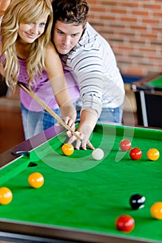 Man teaching his girlfriend how to play pool